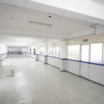 Bright industrial corridor with blue-accented walls and glass-paneled change rooms in a clean warehouse interior RCC Warehouses in Pune.